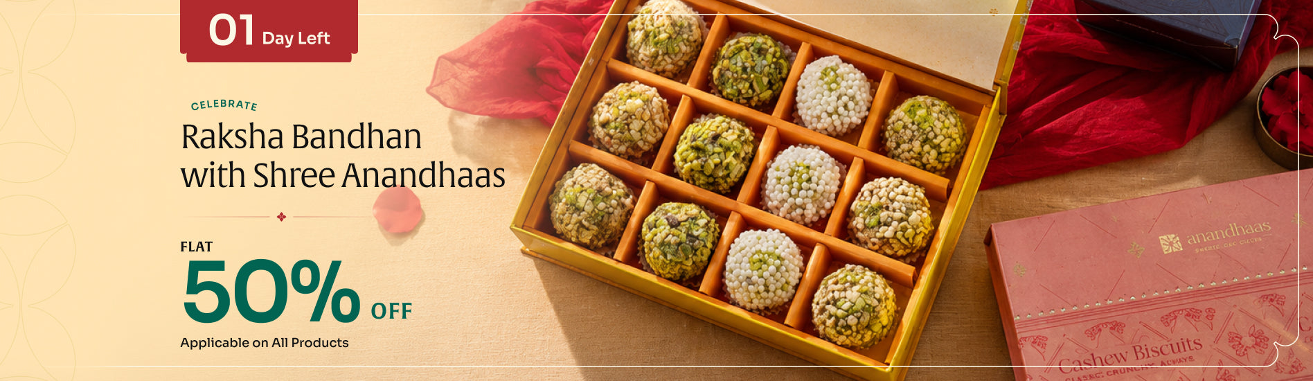 Promotional banner for Raksha Bandhan with Shree Anandhaas offering a 50% flat discount. The right side features an open gold-colored box containing 12 traditional Indian sweet dumplings (thandai) in green and white toppings, set against a warm beige background with festive red fabric and a small plate of sweets.slider_item_7CcXYR